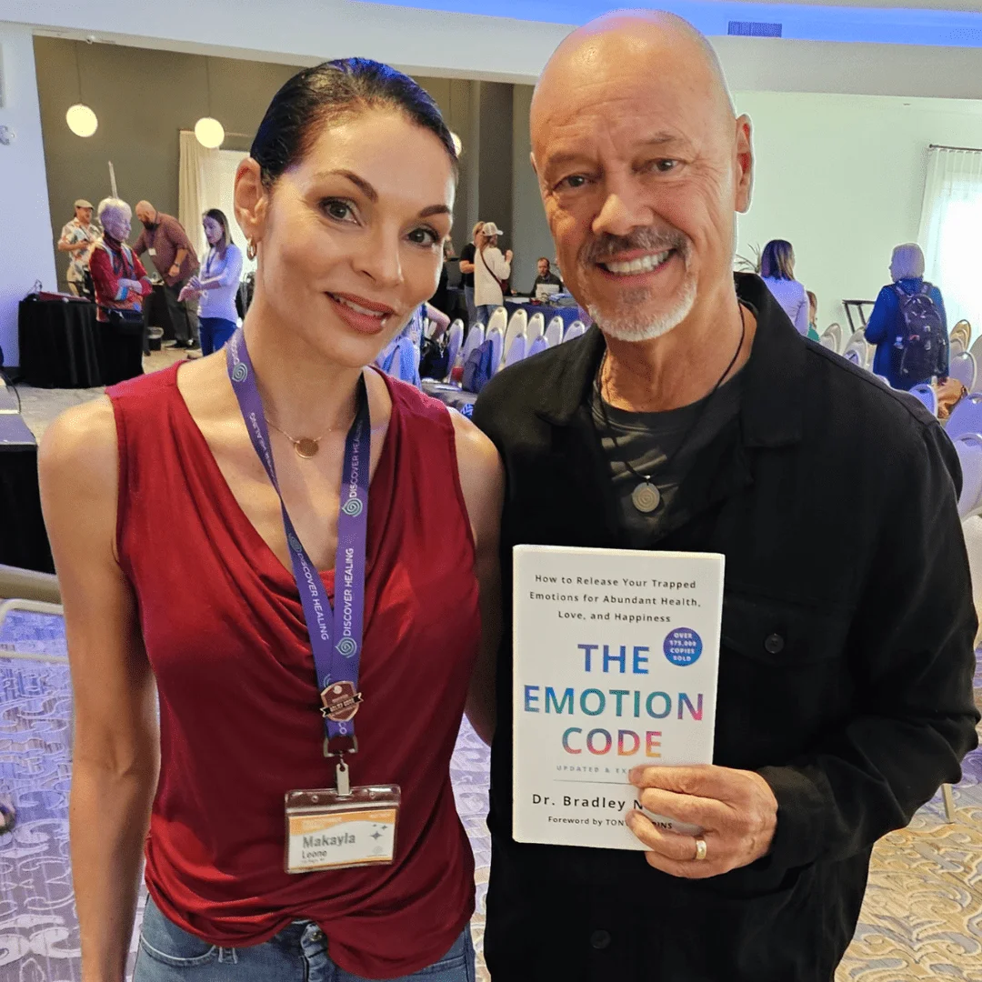 Makayla Léone with Dr. Bradley Nelson, holding The Emotion Code, at the 2024 Practitioner Summit
